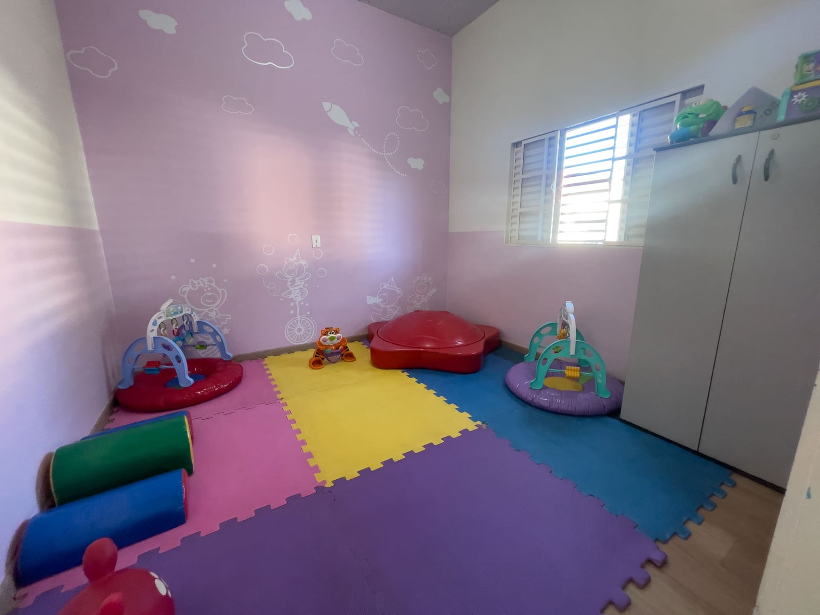 Sala com tapete colorido, brinquedos e módulos para os bebês