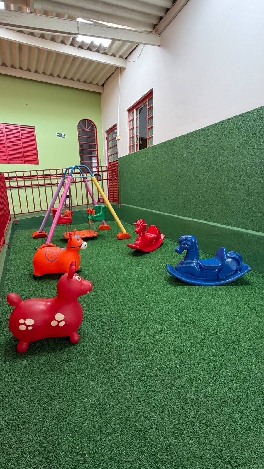 Brinquedos e balanços na área coberta do Berçário