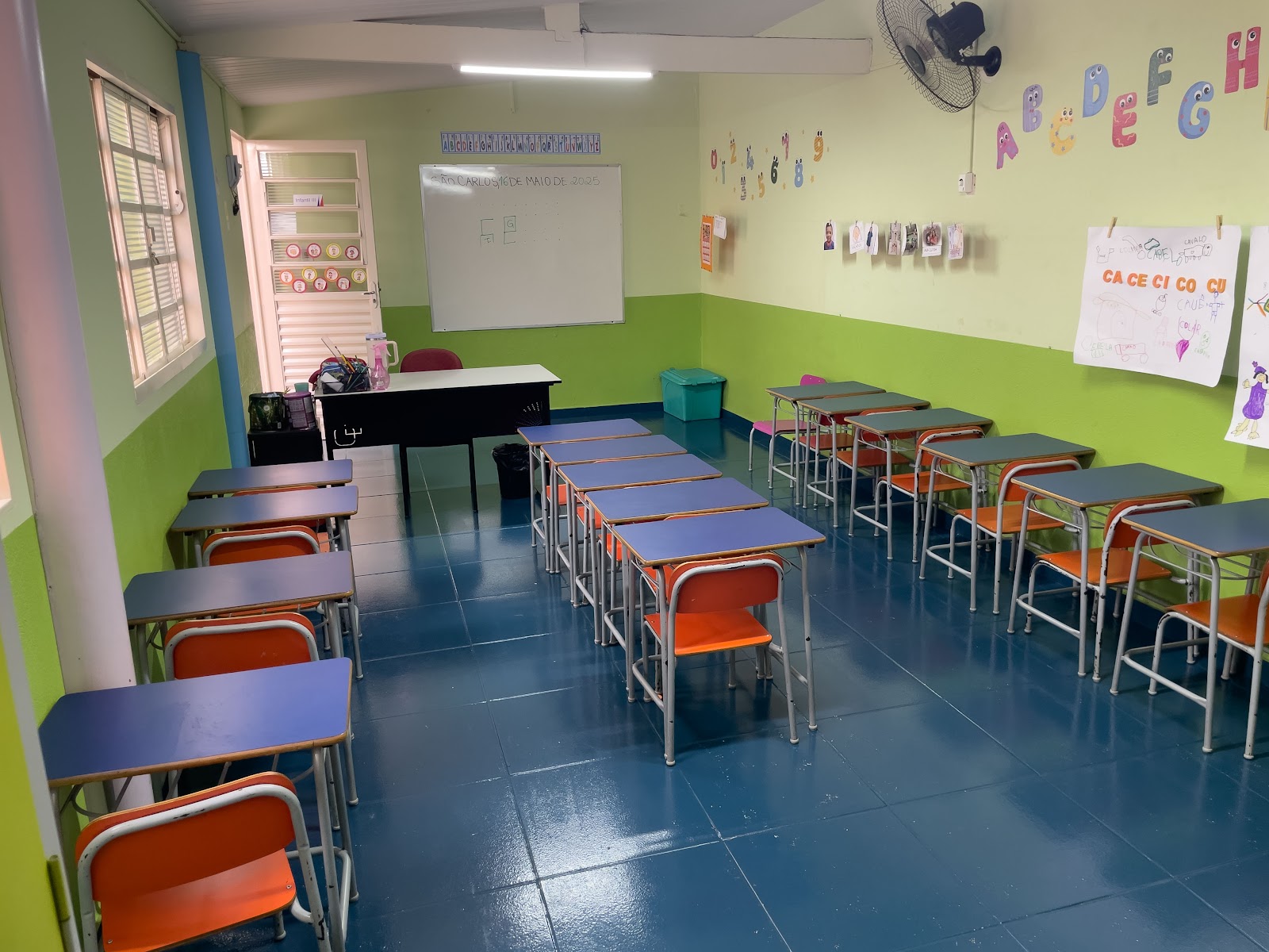 Outra sala de aula da Educação Infantil com carteiras coloridas